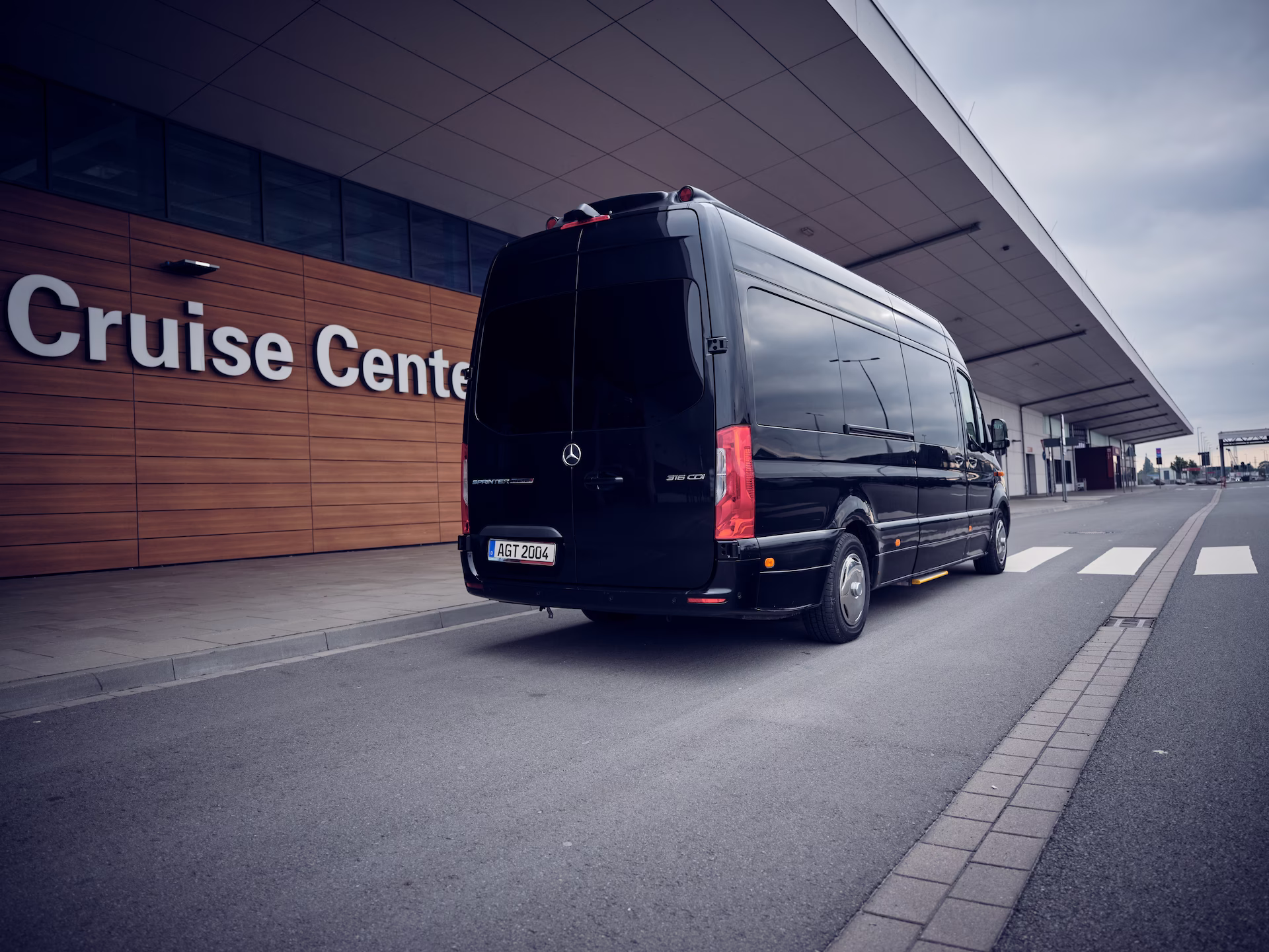 Schwarzer Kleinbus der agt vor einem Kreuzfahrtterminal