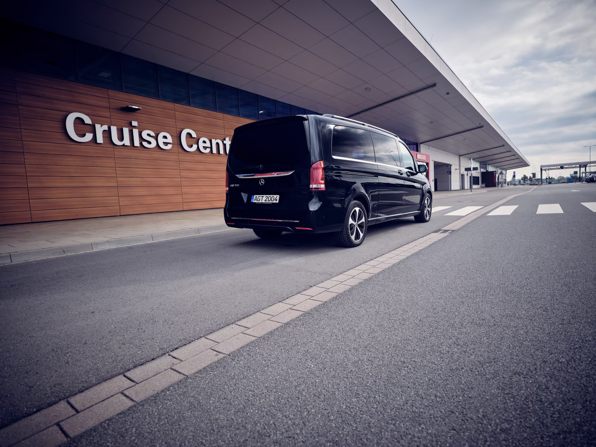 Schwarzer Shuttle-Van vor dem Cruise Center an einem modernen Kreuzfahrtterminal.