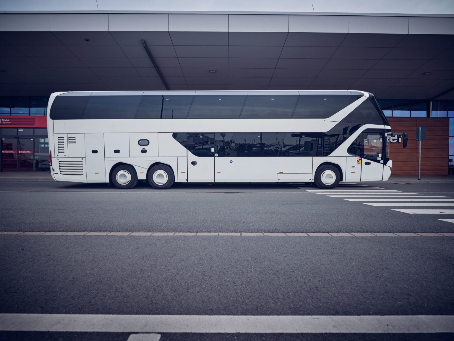 Weißer Doppeldecker-Reisebus vor dem Cruise Center Steinwerder in Hamburg, aufgenommen in einer seitlichen Gesamtansicht.