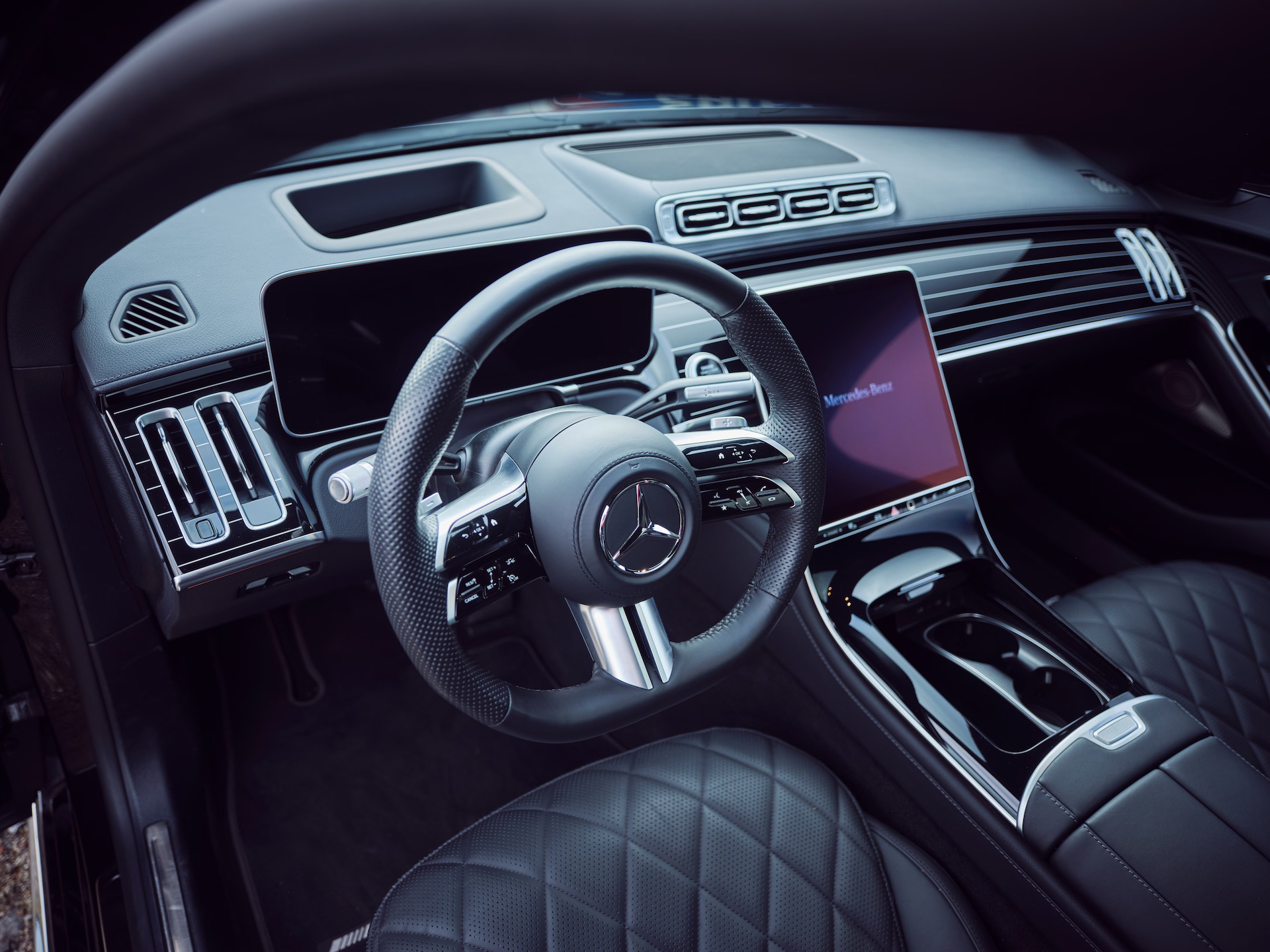 Cockpit einer Luxuslimousine mit Lederlenkrad, Digitaldisplay und hochwertiger Mittelkonsole.