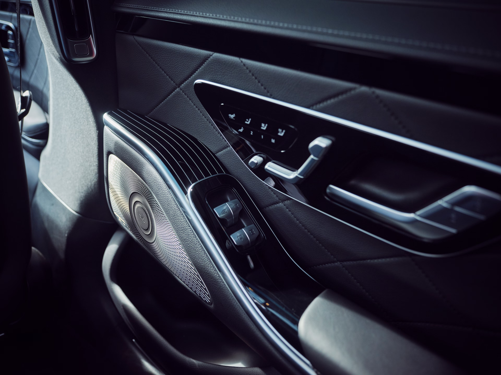 Detailaufnahme der Türverkleidung einer Luxuslimousine mit Lautsprecher, Sitzverstellung und hochwertigen Materialien.