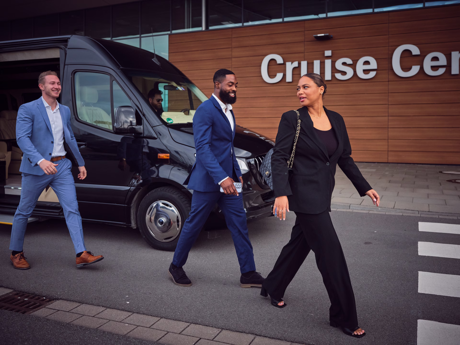 Geschäftsreisende steigen vor einem Cruise Center aus einem schwarzen VIP-Shuttle aus und gehen gemeinsam zum Terminal.