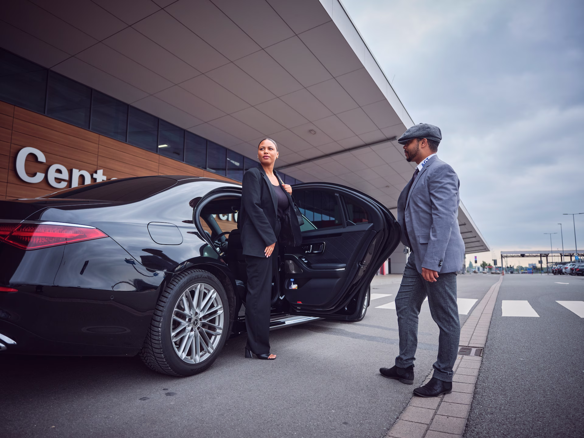 Geschäftskundin steigt aus einer Limousine aus, während der Chauffeur sie am Cruise Center empfängt.