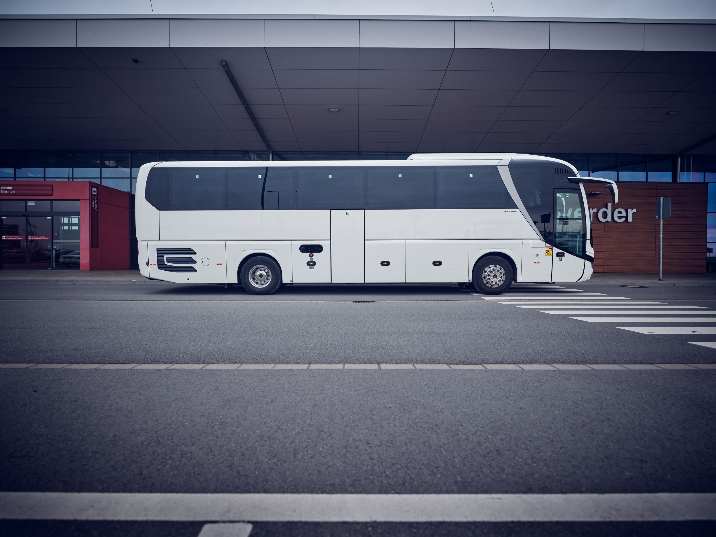 Weißer Reisebus in Seitenansicht vor dem Cruise Center Steinwerder in Hamburg.