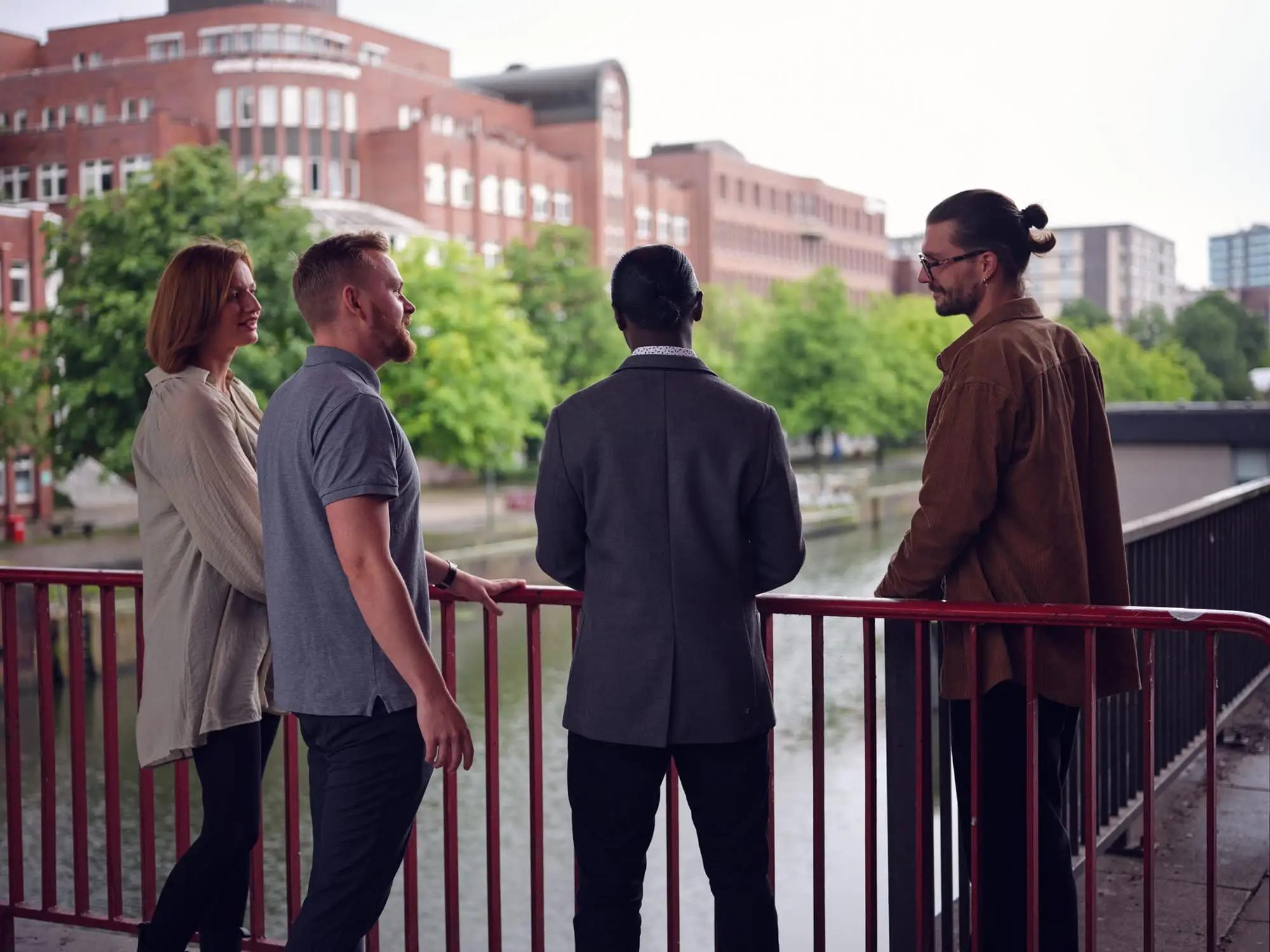 Vier Mitarbeitende der agt an einer Brücke am Wasser
