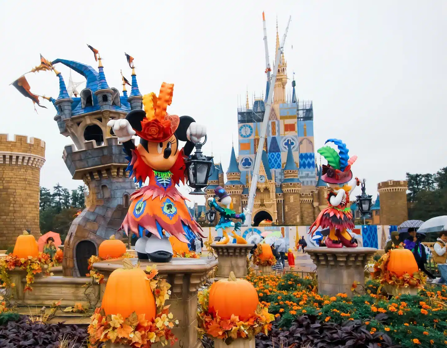 Disney-Schloss in Halloween-Dekoration mit kostümierten Minnie-Mouse-Figuren und Kürbissen in leuchtenden Herbstfarben.