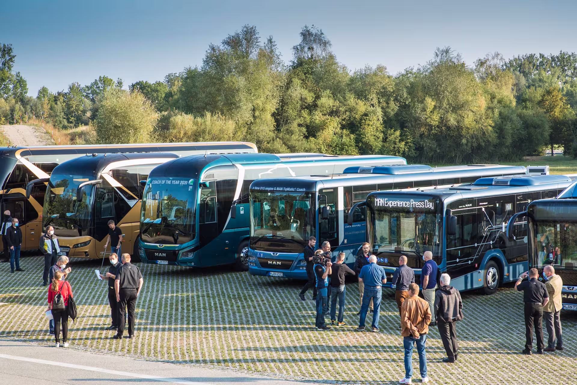 Teilnehmende einer Busfachveranstaltung besichtigen verschiedene Busmodelle und tauschen sich auf dem Ausstellungsgelände über neue Fahrzeugkonzepte aus.
