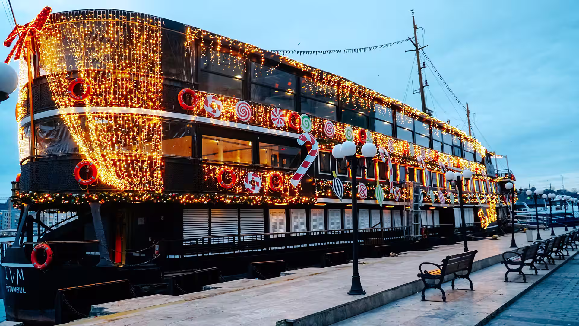 Weihnachtlich geschmücktes Ausflugsschiff mit Lichtervorhang und bunter Deko am Kai in Istanbul.